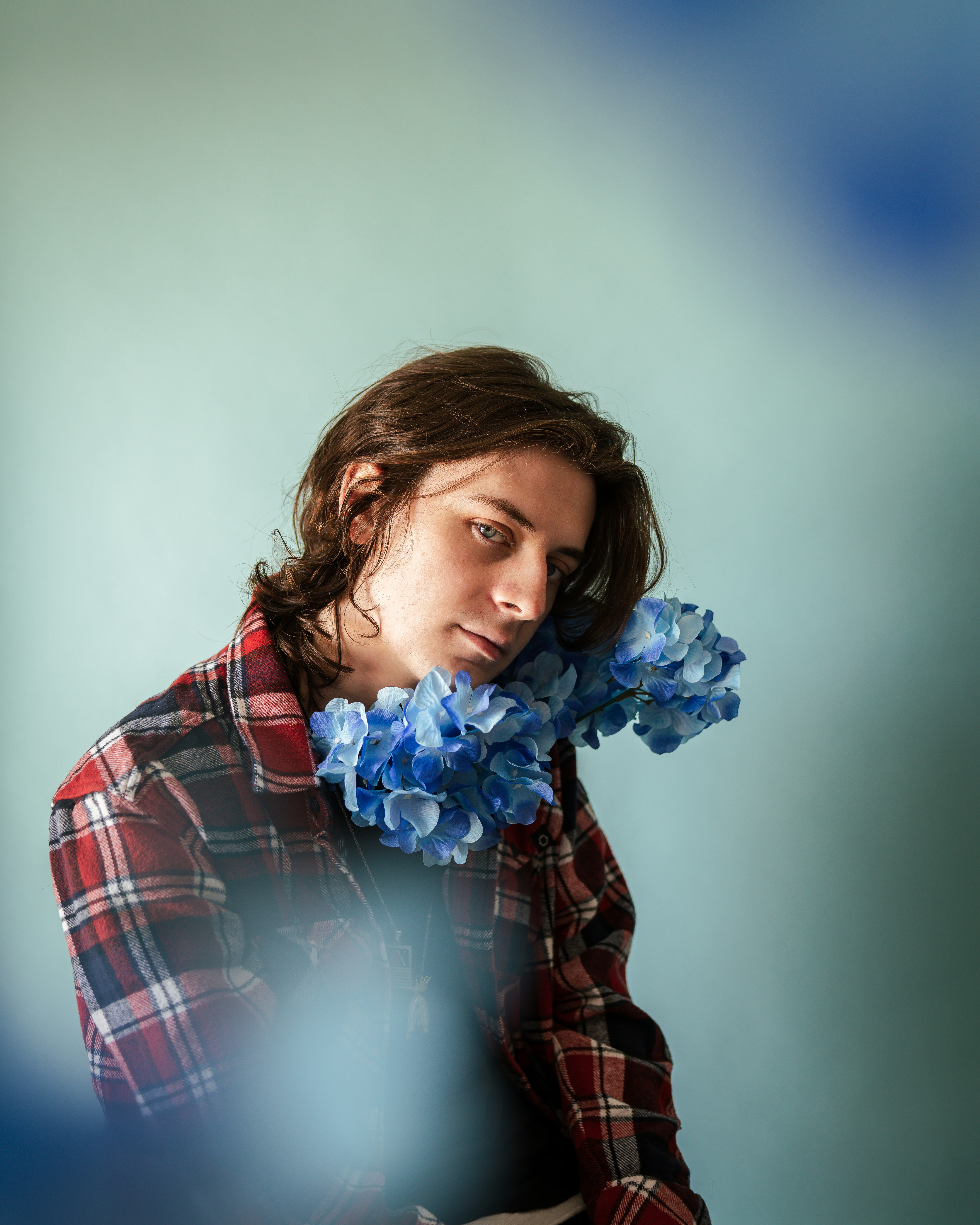 woman in red and black plaid dress shirt holding blue flower